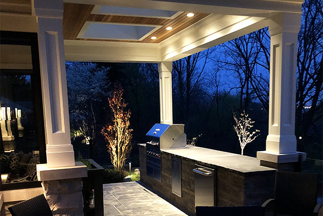 Outdoor kitchen with bbq, access drawers, fridge, and custom deck lighting.